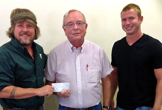 Clint Myers (left), YMCA Camp Clay facilitator, and Tyler Hensley (right), head lifeguard, receive a $750 check from Richard Berkenstock, trustee of the Midwest Electric Community Connection Fund, to buy life jackets for Camp Clay.