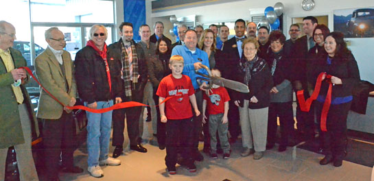 Members of the Van Wert Area Chamber of Commerce Board of Directors and others watch as Eric McCracken cuts the ribbon on Lee Kinstle GM Sales & Service's new showroom. (Dave Mosier/Van Wert independent)