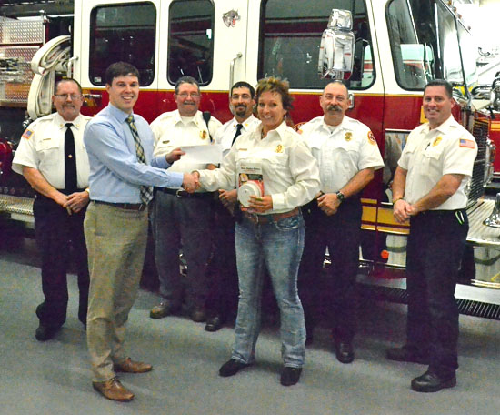 Van Wert County Foundation Executive Secretary Seth Baker (blue shirt) presents a check for $2,000 to Wren Fire Chief Jackie Brandt to provide seed money for the chiefs' No Child Sleeps Unprotected program. Looking one are (from the left) Convoy Fire Chief Gary Kreischer, Willshire Fire Chief D'wight Sheets, Ohio City Fire Chief Brandon Bowen, Van Wert Fire Chief Jim Steele and Middle Point Fire Chief Craig King. Scott Fire Chief Scott Klopfenstein was not present for the photo. (Dave Mosier/Van Wert independent)