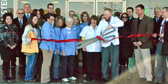 John Joyce, manager of the new Clark's Pharmacy store in Van Wert, cuts the ribbon while company president Tim Clark (third from right) and various city and Van Wert Area Chamber of Commerce Board members look on. (Dave Mosier/Van Wert independent)