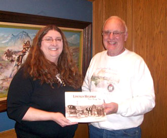 Brumback Library staff member Julie Jones accepts a copy of “The Lincoln Highway, Photos through Time” from Larry Webb of the Lincoln Highway Association. (photo submitted)