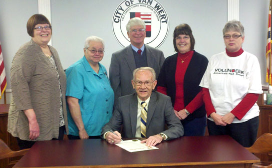 Van Wert Mayor Don Farmer signs a proclamation honoring Red Cross Month while Red Cross Director Sandy Lane (standing left) and Red Cross board members look on. (photo submitted)