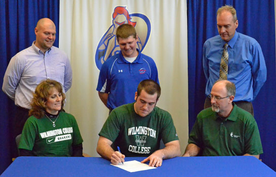 Scott Miller signs his letter of intent flanked by his parents, Nick and Lisa Miller, while coaches James Lautzenheiser and Jared Owens and Athletic Administrator Dave Bowen look on. (Dave Mosier/Van Wert independent)