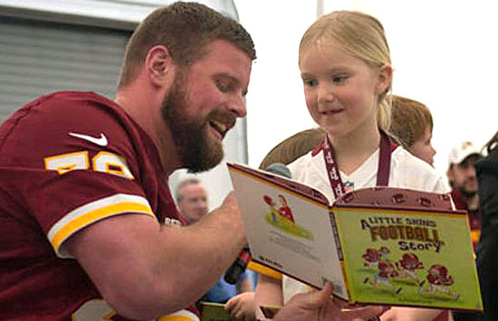 Kory Lichtensteiger reads to a fan during a Redskins Kids Club event. Lichtensteiger, a center for the Washington Redskins and a Crestview High School graduate, will host his annual football camp this Saturday at Crestview. (Washington Redskins photo)