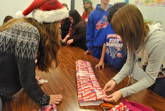 Juniors Amanda Cole and Leslie Skelton help students from Reindel's and Jackie Deitering’s classes wrap presents to give to each student’s parents. (Photo by Megan Hartman.)