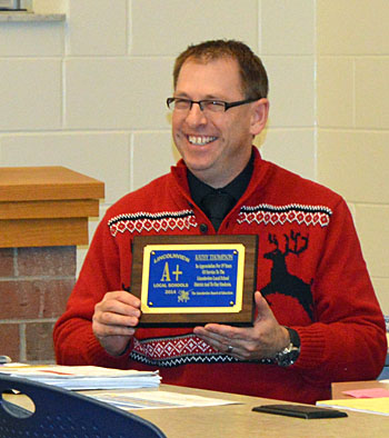 Lincolnview Superintendent Jeff Snyder holds a plaque honoring Kathy Thompson, who is retiring at the end of the month. Thompson had a sick child and couldn't attend the meeting. (Kelsey Clemons/Van Wert independent)