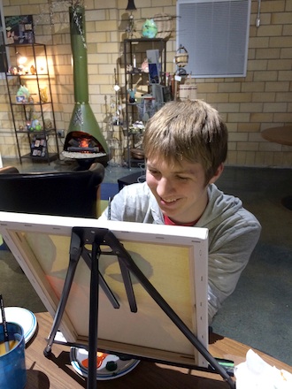 Justin Hammond, Van Wert, smiles behind his painting. Justin is able to complete free paintings because of volunteer hours spent at the Wassenberg Art Center. (Photo submitted.)