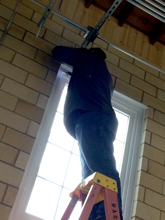 Rich Davis of John Rager Home Improvement drills through the tough ceramic blocks to install the hardware which hold floor-length drapes at the Wassenberg Art Center. (Photo submitted.)