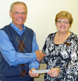 Tom Schlenker, Midwest Electric Community Connection Fund treasurer, gives a $1,000 donation to Tammy Branham-Cripps, executive director of YWCA of Van Wert County, to support the Youth Food Program and Transitional Housing Program. (photo submitted)