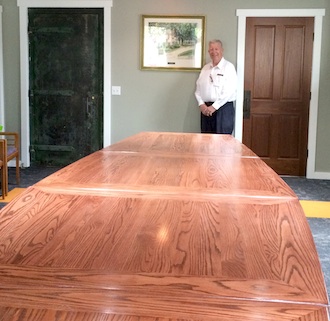 Larry Wendel stands behind the 14-foot, modular boardroom table he and his wife Gloria had specially crafted for the Wassenberg Art Center. The table was made by Dave Salway, Rockford. (Photo submitted.)