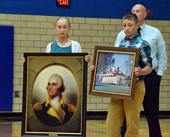 Crestview Middle School students hold artwork donated to the district while teacher James Lautzenheiser is in the background. (Dave Mosier/Van Wert independent)