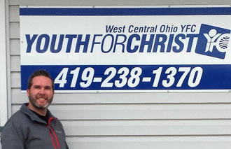 Brad Petrie, new Campus Life director at Van Wert  High School, poses with the local Youth for Christ sign. (photo submitted)