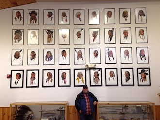  Brent Stevens, owner of the Faces of Little Bighorn exhibit at the Wassenberg Art Center poses under some of the prints on view at Crazy Horse Memorial in Custer, S.D. The portraits were painted by the late David Humphreys Miller, a Van Wert native.  Many of Miller’s works are on permanent display at the Wassenberg Art Center. (Photo submitted.) 