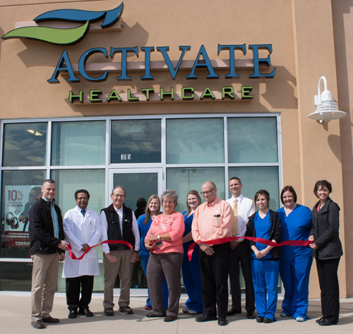 Dianne Cooper cuts the ribbon on Cooper Farms' new healthcare clinic in the Towne Center retail development on  Wednesday, while Cooper officials and clinic workers look on. (photo submitted)