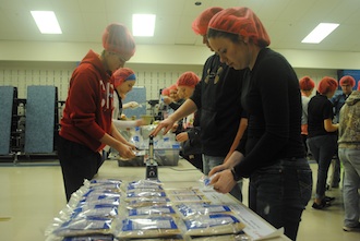 Students package meals for people in Haiti.  (Photo caption.)