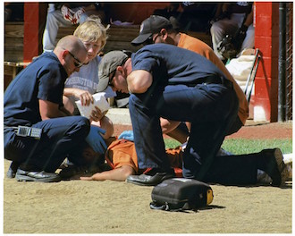 An example of photojournalism, where the picture helps tell the story: EMS staff attends to a Little League catcher beaned by a foul ball. (Photo by Rex Dolby.)