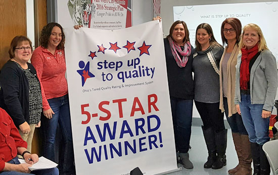 Van Wert Early Childhood Center Principal Lori Bitner (left) and VWECC staff members pose with a sign indicating the school received a five-star rating on the Step Up to Quality program. Scott Truxell/Van Wert independent