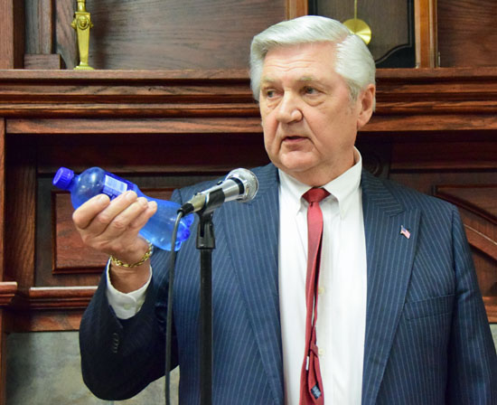 Van Wert Mayor Jerry Mazur holds up a bottle of water, the cost of which he said would equal what a city resident making $50,000 would pay a week in additional income taxes Dave Mosier/Van Wert independent