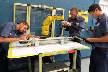 Vantage juniors Clay Schnipke (Ottoville), Robert Germann (Crestview), and Tyler Brecht (Continental) work as a team on the Fanuc automated material handling robot in the Industrial Mechanics lab.  Come to Open House on Monday, February 27, from 5-7:30 p.m., to see more demonstrations in all 18 career technical education labs. (Vantage photo)