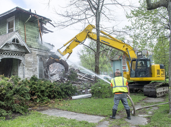 A worker hoses down a house at 421 N. Market St. to reduce the amount of dust created as the house is being demolished. Bob Barnes/Van Wert independent